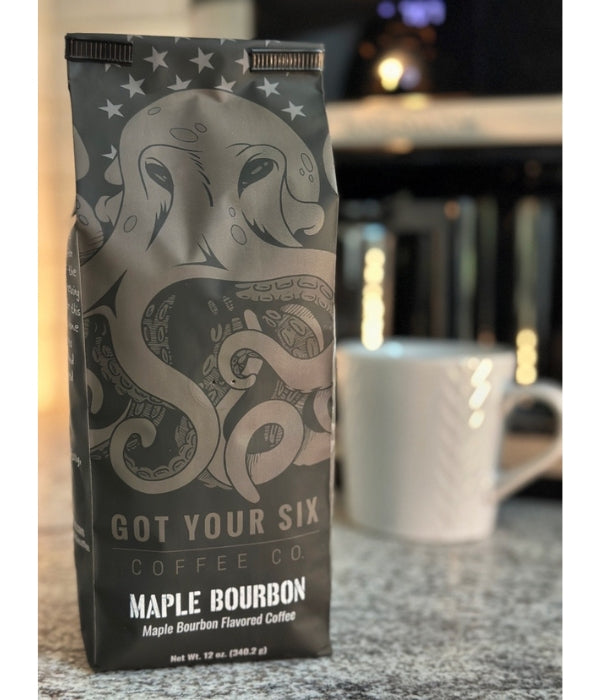 A bag of Got Your Six Coffee Company's Maple Bourbon coffee beans with a white coffee cup in the background.